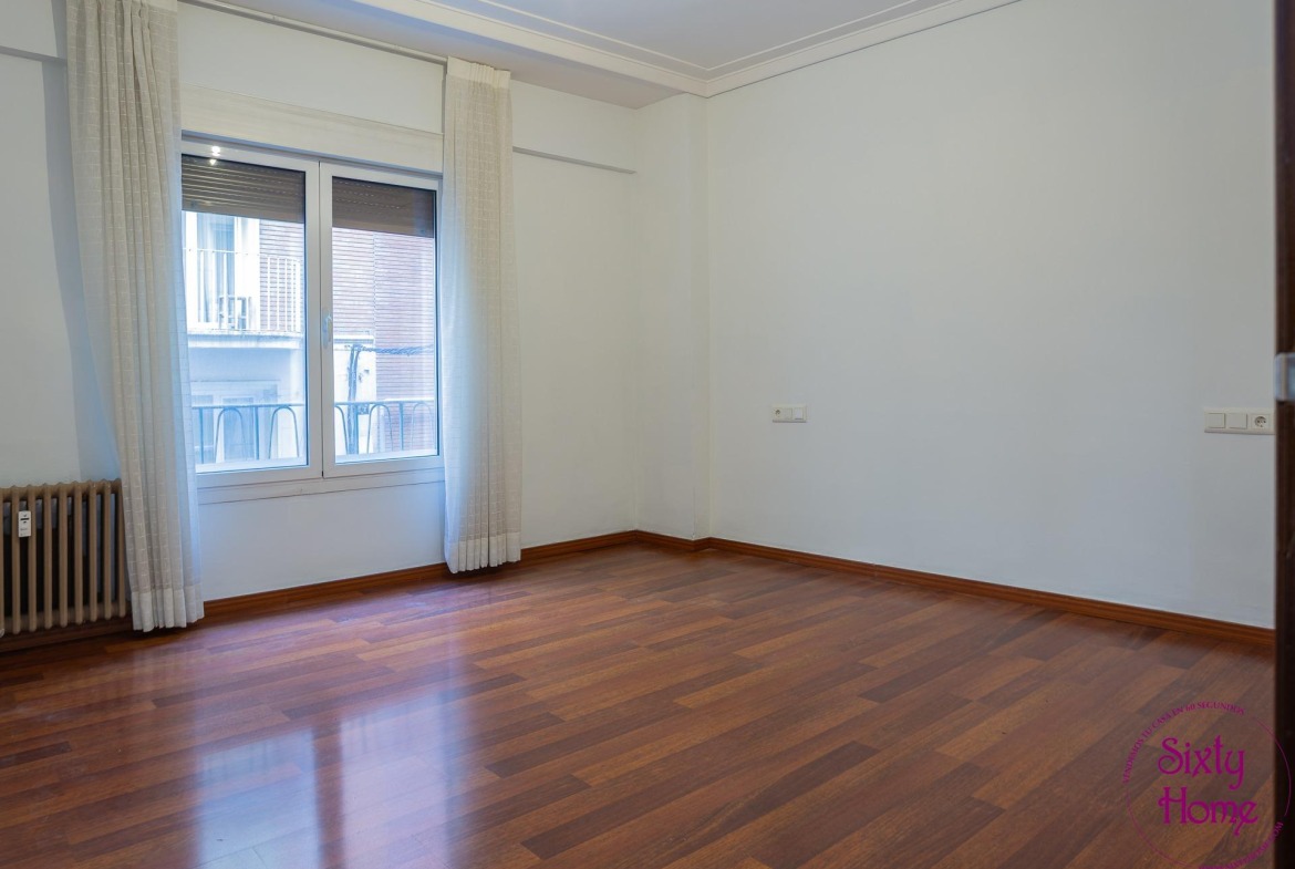 Habitación vacía de un piso en venta, con suelo de madera.