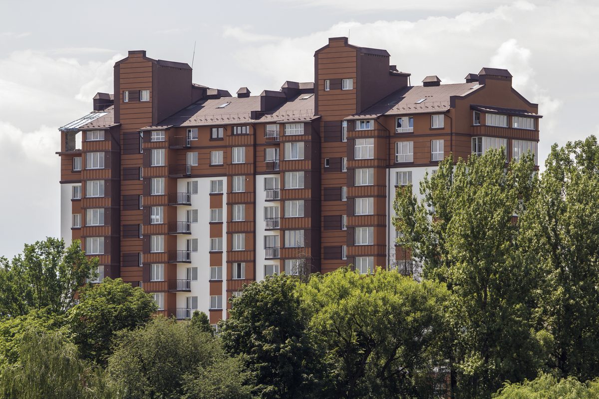 Edificio de pisos de ladrillo rodeado de árboles, para calcular la ganancia patrimonial por la venta de un inmueble