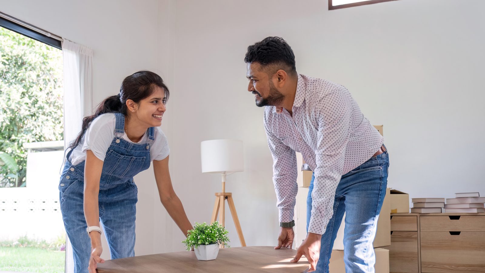 Pareja colocando los muebles entre cajas de mudanza en el salón de su vivienda