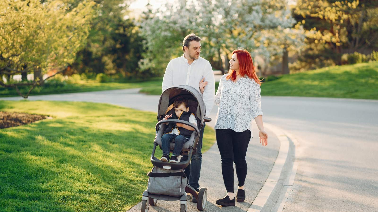 Familia joven paseando por el parque de un barrio residencial, uno de los factores al elegir barrio en Zaragoza