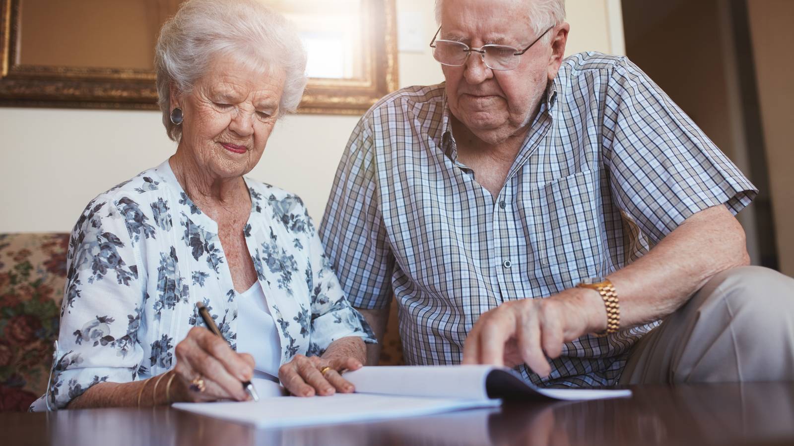 Pareja mayor haciendo cuentas para liquidar la plusvalía municipal al vender su vivienda