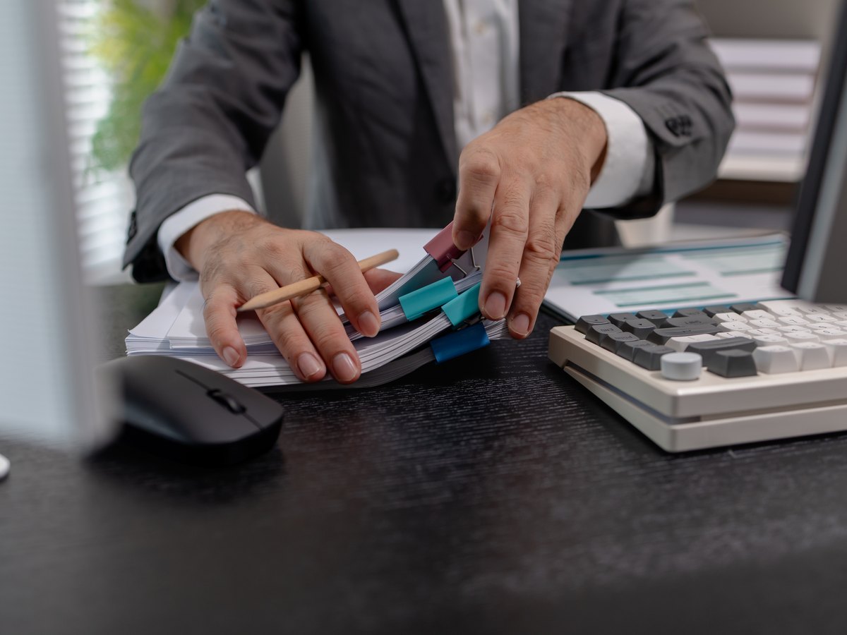 ¿Cuánto cuesta tasar una vivienda en Huesca? Precios publicados y quién paga 1 Hombre revisando informes en carpetas junto a una calculadora: cuánto cuesta tasar un piso en Huesca