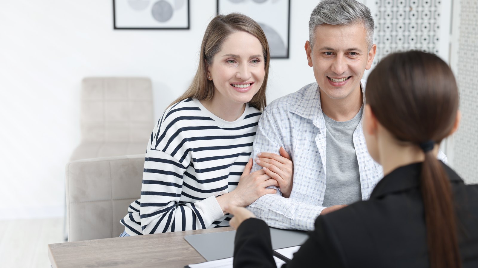 Pareja sonriente reunida con una asesora: gastos de comprar una vivienda en Huesca