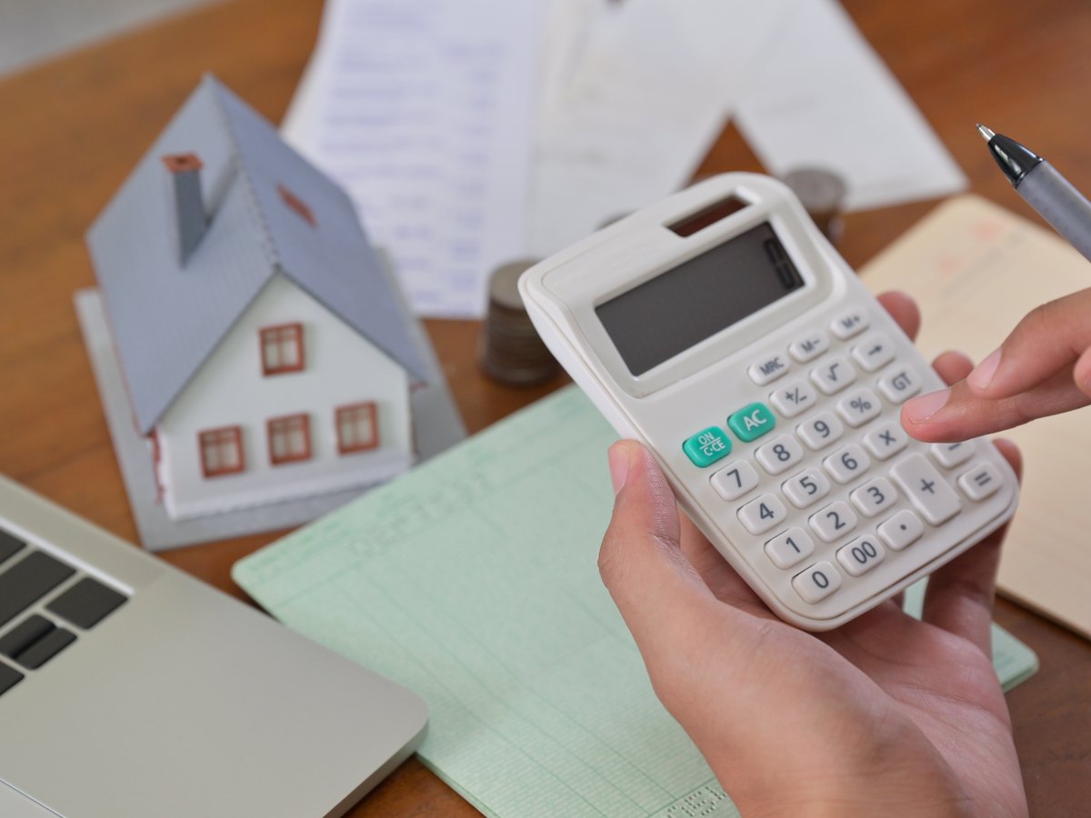 Gastos de comprar una vivienda en Huesca: cuánto pagas además del precio 1 Calculadora, casita y documentos sobre la mesa para calcular el ITP al comprar un piso en Huesca