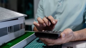Técnico con calculadora junto a la maqueta de una vivienda: precio de una tasación de vivienda en Huesca